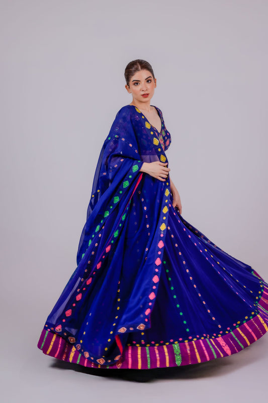 Woman wearing a blue traditional outfit with colorful patterns on a gray background